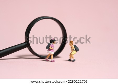 Miniature people toy figure photography. Children curiosity concept. Two girl kindergarten students standing in front of magnifier glass. Isolated on pink background. Image photo