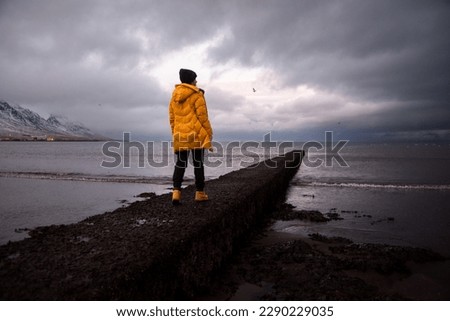 Young girl traveling in the winter in Iceland in a yellow jacket