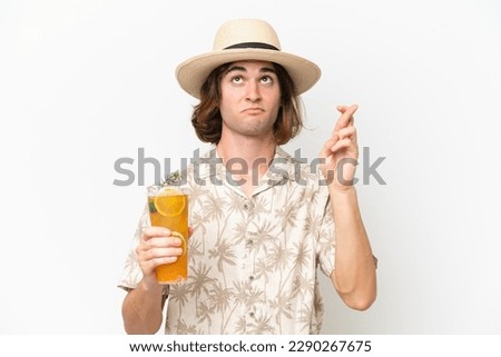 Young handsome man holding a cocktail isolated on white background with fingers crossing and wishing the best