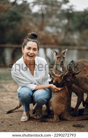 Woman in the reserve is playing with a kangaroo