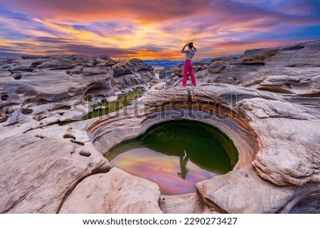 Young female tourists stand to watch the sunrise at Sam Phan Bok, Ubon Ratchathani, Thailand. Royalty-Free Stock Photo #2290273427