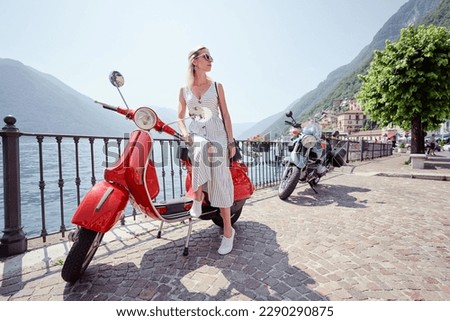 Riding lifestyle. Outdoor portrait of pretty young woman in dress sitting on scooter.