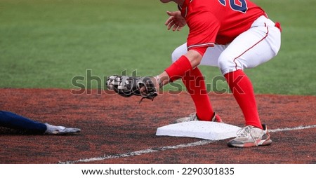 Third baseman ready to tag out the arm of a sliding runner during a high school baseball game.