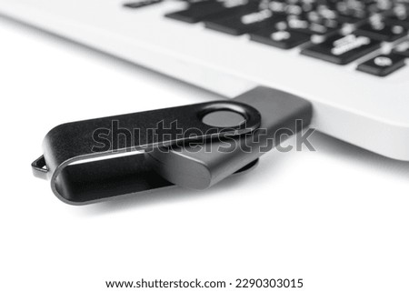 Laptop with black USB flash drive isolated on white background