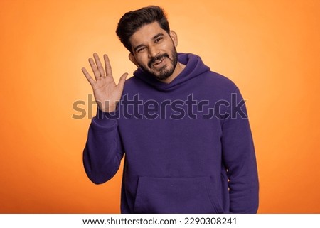Hello. Come here, join us. Welcome. Hindu bearded man showing inviting gesture with hands, ask to join, beckoning to coming, gesturing goodbye. Handsome indian guy isolated on orange studio background Royalty-Free Stock Photo #2290308241