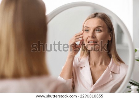 Closeup Shot Of Middle Aged Beautiful Woman Looking In Mirror At Home, Attractive Mature Female With Flawless Skin Inspecting Her Face While Making Daily Beauty Routine, Selective Focus Royalty-Free Stock Photo #2290310355