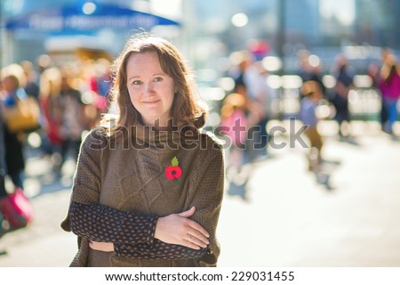 Girl wearing red remembrance poppy on a street of London, UK