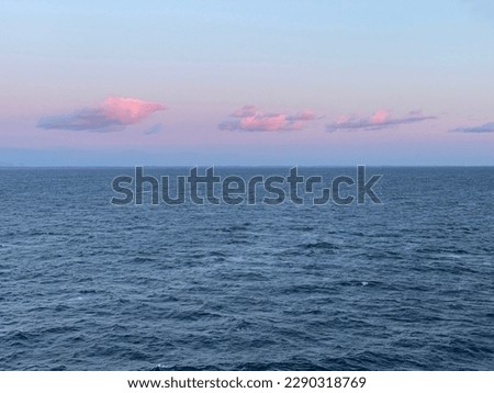 The sun goes down on the Skagerrak on a cold but sunny winters day near Nordkoster in Sweden. There are pink colored clouds on the sky in the background. Seen from a ferry ship. Royalty-Free Stock Photo #2290318769