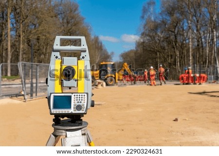 Yellow equipment set out on tripod on building site against cloudless blue sky. Construction site surveying engineering equipment, EDM, tacheometer set out on tripod site ready for setting out. Royalty-Free Stock Photo #2290324631