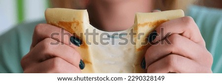 Close-up of female hands holding pancake with cheese filling. Woman stretching slapjack with cheese. Home cooking and healthy food concept Royalty-Free Stock Photo #2290328149