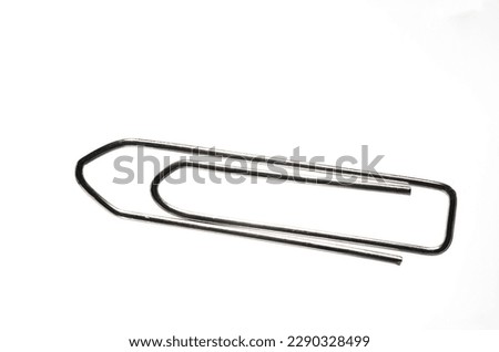 Extreme close up of large silver metal paper clip against white background with copy space as concept for office paperwork and administration Royalty-Free Stock Photo #2290328499