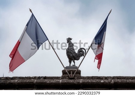 Statue of a rooster, emblem of France, with two French flags Royalty-Free Stock Photo #2290332379