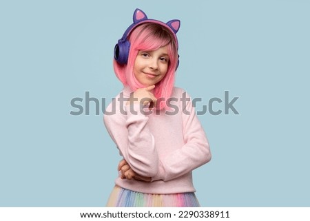 Portrait cute teen school girl. Zoomer. Alternative look. Young female teenage in pink wig and modern headphones on light blue studio background.