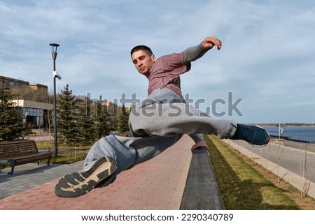 Sport man practicing parkour in urban space. Parkour athlete jumping over the railing. Active lifestyle. Outdoor acrobatics Royalty-Free Stock Photo #2290340789