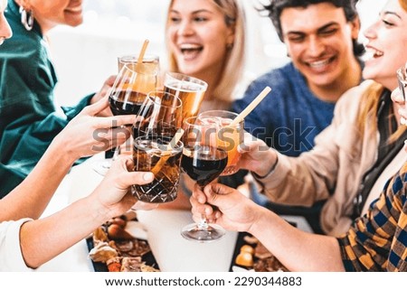Group of friends toasting fancy cocktails together sitting at bar restaurant table-Happy young people celebrating party enjoying happy hour with wine and beer-Food and beverage lifestyle concept


