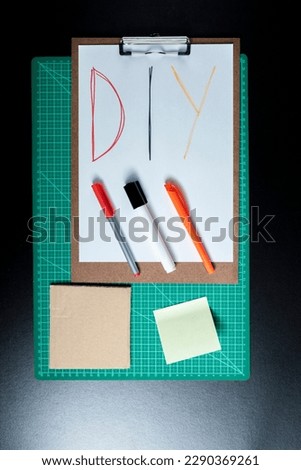 Handmade products cutting base with diy writing. Clipboard, papers, cardboard, scissors and colored adhesive. DIY concept. Craft concept.