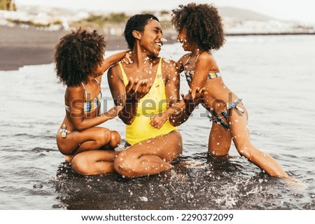 African sister twins having fun with mother on the beach - Focus on right mom hand