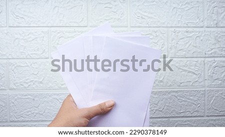 Woman's hold envelope over white wall background.