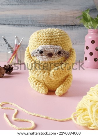 a yellow plushie homemade sloth from crochet with blurry and unfocused background