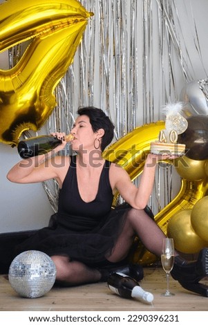 Caucasian woman drinking champagne from bottle celebrating her 40 birthday in a party.