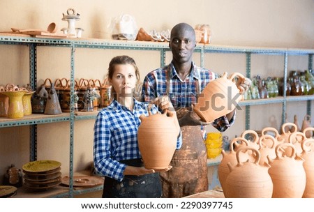 Two positive smiling potters in the process of work at the workshop. High quality photo