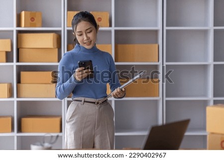 Portrait of Starting Asian female small businesses owners SME entrepreneur working at Laptop in home Warehouse, online marketing, packing boxes, SME sellers, concept, e-commerce team, online sales.	