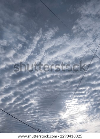 a photo of stratus clouds that are so beautiful and slightly obstructed by electric pole cables that interfere with the view