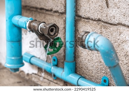 A Mechanic Plumber is Repairing a Leaking Water Pipe Tap Near the Water Meter. Royalty-Free Stock Photo #2290419525