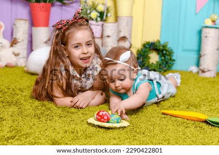 Funny girl with eggs basket. Children celebrating Easter. Happy easter card. Surprised girl holding a wicker basket with colored eggs. Cute child girl on Easter day holding her friend little rabbit.