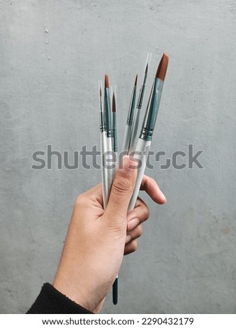 Hand holding white paint brush