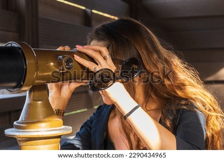 Shot of a young beautiful woman looking trough military binoculars