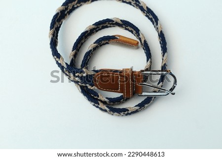 Men's fashion elastic belt with beige blue white and brown webbing pattern fastened with metal buckle.