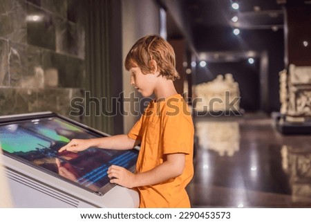 Boy operating a large touch screen indoors