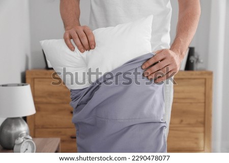 Man changing pillowcase at home, closeup. Domestic chores Royalty-Free Stock Photo #2290478077