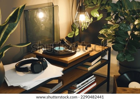 Stylish turntable with vinyl record on table in cozy room Royalty-Free Stock Photo #2290482441