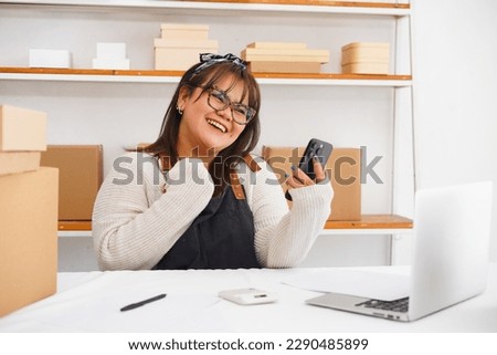 Photo of  excited young female self employed  sitting at work desk focused on mobile phone screen. Women young enterpreneur arranger reading email with profitable offer from potential customer Royalty-Free Stock Photo #2290485899