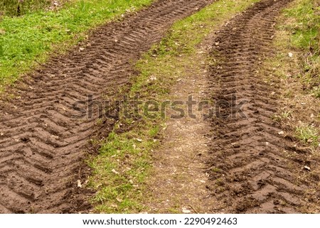 Traces of a tractor in the mud in a wet meadow Royalty-Free Stock Photo #2290492463