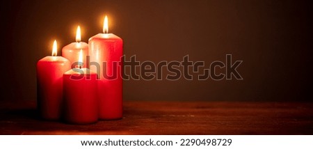 four red candles against dark background with copy space  for banner, panorama or border with copy space