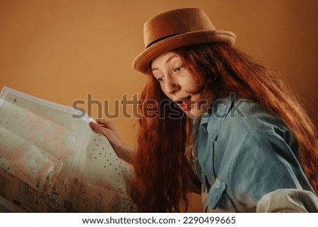 Close up of beautiful red head looking at the map  while standing at the studio