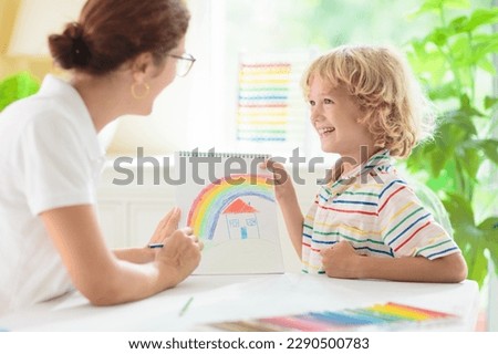 Child drawing. School kid painting a picture. Little boy with colorful pencils doing homework in white sunny room. Kids draw and paint. Preschool art and crafts.