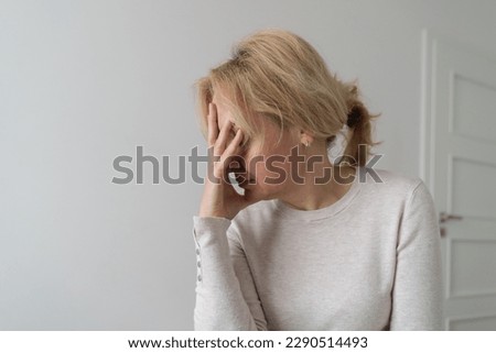 Depressed mature woman at home. Sad face with hands. Mental health problems, gaslighting or bulling at home Royalty-Free Stock Photo #2290514493