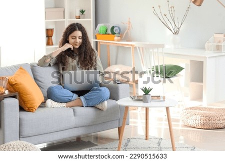 Teenage girl using laptop on sofa at home Royalty-Free Stock Photo #2290515633