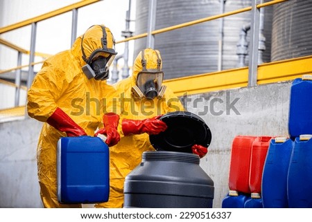 Chemicals manufacture. Workers in protective chemical suit and gas mask dealing with dangerous or hazardous materials and acids. Royalty-Free Stock Photo #2290516337