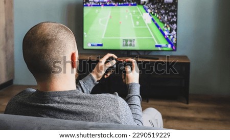 Guy playing a video game console. Game is football. Back view. Selective focus