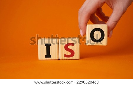 ISO standards quality control symbol. Concept word ISO on wooden cubes. Businessman hand. Beautiful orange background. Business and ISO concept. Copy space.