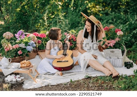 Beautiful mother and daughter family on picnic with guitar at summer spring sunny day