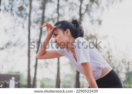 An Asian woman is exhausted and wipe sweat after running, jogger, work out or do morning exercising. Concept of city lifestyle, healthy sport, tired and breathing, refreshment and sweaty. Royalty-Free Stock Photo #2290522439