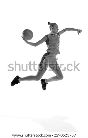 Black and white image of young sportive girl during basketball game, playing, training against white studio background. Concept of professional sport, hobby, healthy lifestyle, action and motion