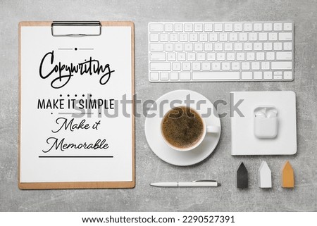 Paper with phrase Copywriting Make It Simple Make It Memorable, keyboard and coffee on grey textured table, flat lay