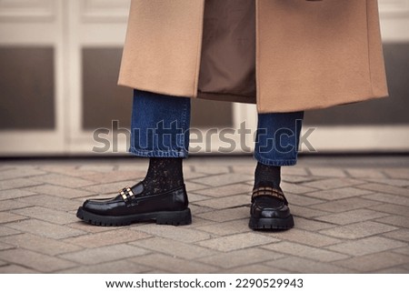Close up female legs in jeans, stylish black loafers shoes and socks, street style fashion Royalty-Free Stock Photo #2290529943